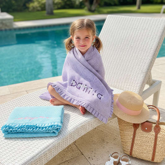 Personalized seersucker kids towel with ruffle trim and embroidered name
Close-up of ruffle edge detail on girls beach towel
Custom name embroidery on soft cotton seersucker towel
Folded kids towel showing texture and ruffle trim
Personalized girls beach towel styled for summer vacation
Lightweight cotton towel with ruffle edge for kids
